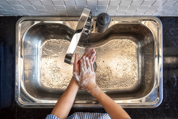 Κορυφή άποψη ασιατική γυναίκα πλύσιμο των χεριών με βρύση νερού στην κουζίνα στο σπίτι, φροντίδα της υγείας του Covid-19 πανδημία, τον καθαρισμό και ανέμελη έννοια - Φωτογραφία, εικόνα