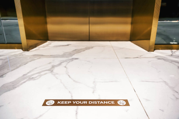 Κρατήστε την απόστασή σας Κείμενο στο πάτωμα μπροστά από ανελκυστήρα ή elevato - Φωτογραφία, εικόνα