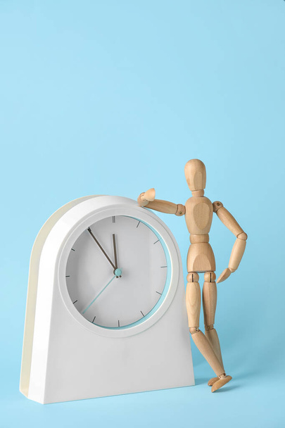 Wooden mannequin with clock on color background - Photo, Image