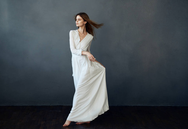 vrouw in wit jurk dans prestaties luxe glamour grijs achtergrond - Foto, afbeelding