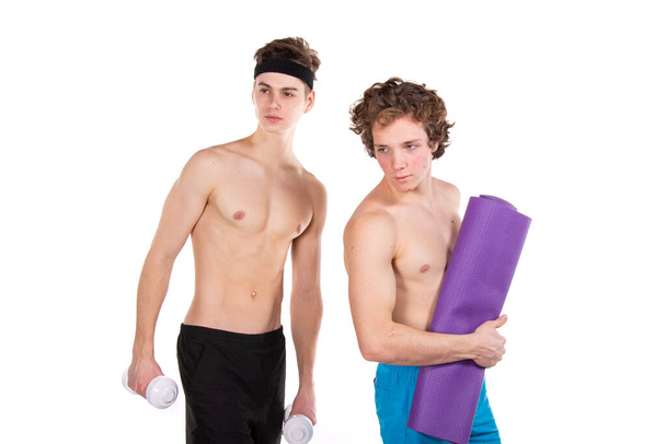Γυμναστική και υγιεινό τρόπο ζωής. Δύο νεαροί ελκυστικοί μαθητές στο γυμναστήριο. Λευκό φόντο. - Φωτογραφία, εικόνα