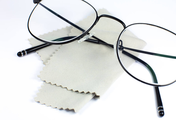 Black frame glasses with glasses cleaning cloth on a white background. Close up photo. - Photo, Image