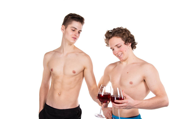 Διακοπές και Σαββατοκύριακα. Νεαρό ελκυστικό ζευγάρι που πίνει κόκκινο κρασί. Λευκό φόντο. - Φωτογραφία, εικόνα
