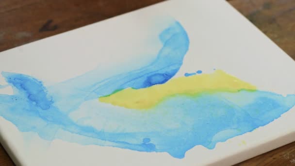 Fluide Kunst. Abstrakte blaue und gelbe Malerei. Nahaufnahme einer Künstlerin, die gelbe und blaue Farben mit Wasserspray mischt - Filmmaterial, Video