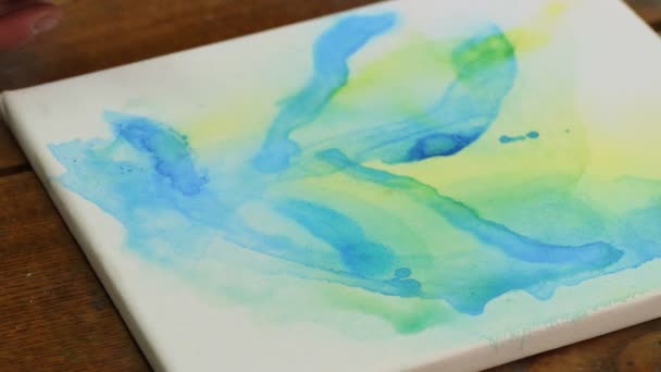 Kadın ressamın yakın çekimi soyut bir resim çizer, ıslak tuval üzerinde mavi boya kullanır. - Video, Çekim