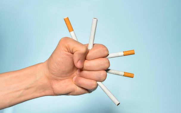 In der Hand viele Zigaretten und blauer Hintergrund. Schluss mit dem Rauchen, Weltnichtrauchertag am 31. Mai. Selektiver Fokus - Foto, Bild