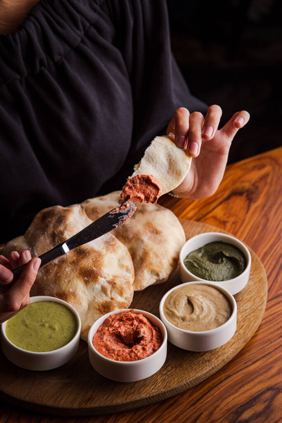 view of a woman dipping pita slices in a sauces - Photo, Image