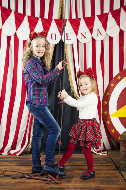 Due ragazze bionde salgono la scala di corda sullo sfondo del paesaggio circense. Giornata mondiale del circo. Nuovo concetto anno - Foto, immagini