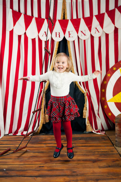 Mała blondynka bawiąca się i skacząca na tle cyrkowej scenerii. Światowy Dzień Cyrku. Koncepcja nowego roku - Zdjęcie, obraz