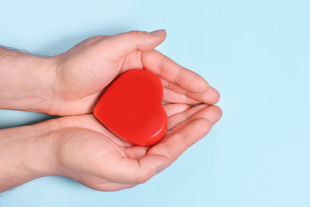 Red heart in man's hands isolated on blue background. Healthcare and hospital medical concept. Symbolic of Valentine day.Top view with space for text. - Photo, Image