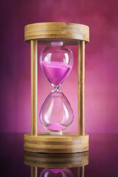 Pink sand hourglass on pink background - Photo, Image