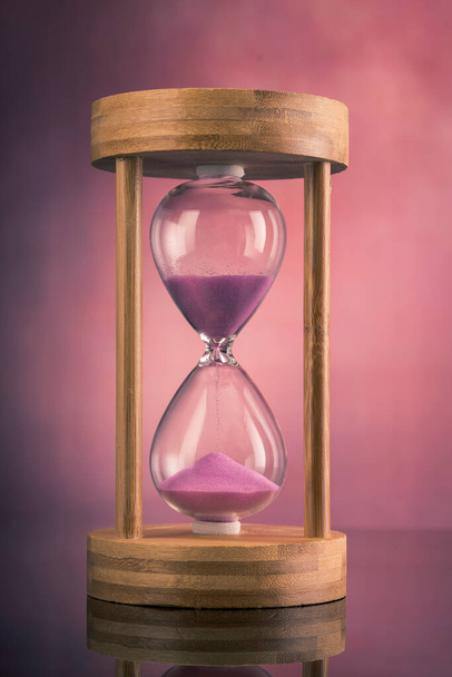 Розовые песочные часы на розовом фоне - Фото, изображение