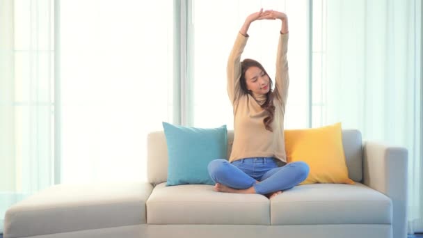 metraje de hermosa joven asiática mujer estiramiento en sofá en casa - Metraje, vídeo