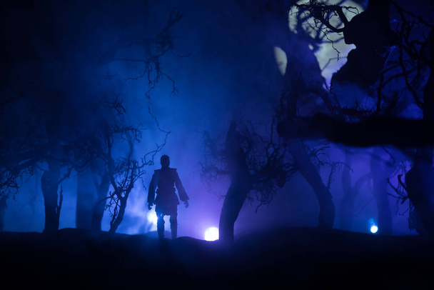 Силуэт человека, стоящего в темном лесу. Концепция Хэллоуина ужасов. Странный силуэт в темном жутком лесу ночью - Фото, изображение