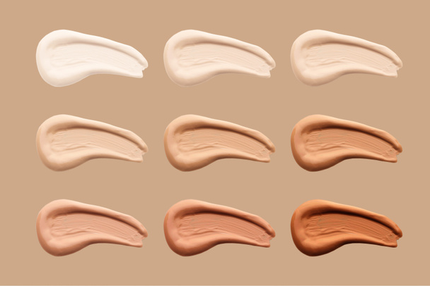Smears of liquid foundation isolated on brown background. Set of different skin tone cream swatches for makeup. - Photo, Image