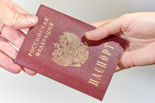     Рука женщины дает русский паспорт мужчине крупным планом.                             - Фото, изображение