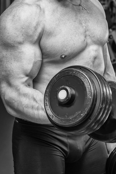 Man working with dumbbells in the gym - Foto, afbeelding