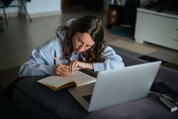 Young woman at home use laptop and write notes - Photo, image