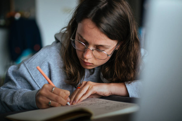 Jeune femme à la maison utiliser un ordinateur portable et écrire des notes - Photo, image