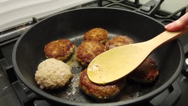 Hús szeleteket főzök. Házi főzés. A szaftos húsdarabokat olajban sütik egy fekete serpenyőben.. - Felvétel, videó