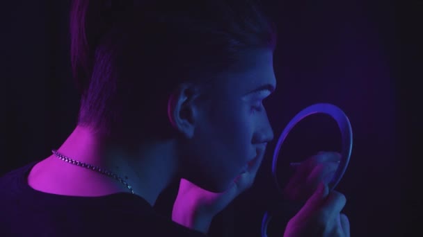 Sleep kunstenaar - jonge man tekening nieuwe wenkbrauwen en kijken naar zichzelf in de spiegel - blauw en paars neon verlichting - Video