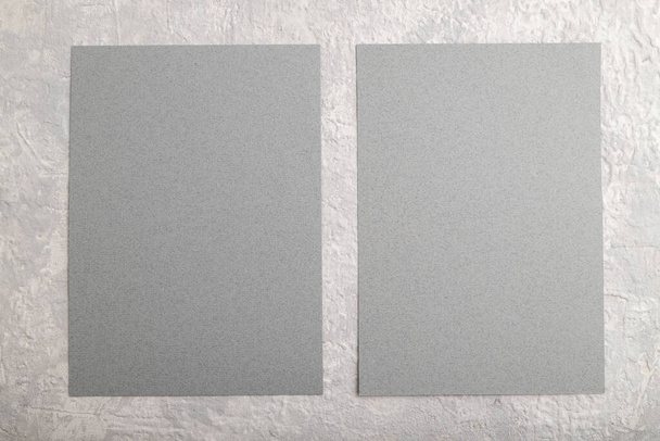 Tarjeta de visita de papel gris, maqueta sobre fondo de hormigón gris. espacio en blanco, plano, vista superior, bodegón, copia. - Foto, Imagen