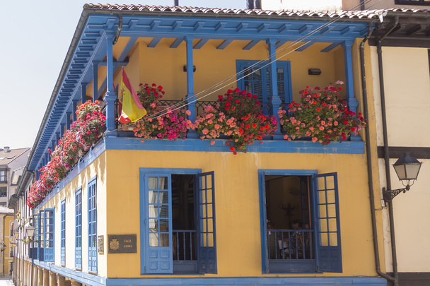 яскраво-кольоровий будинок з балконом, повним квітів
 - Фото, зображення