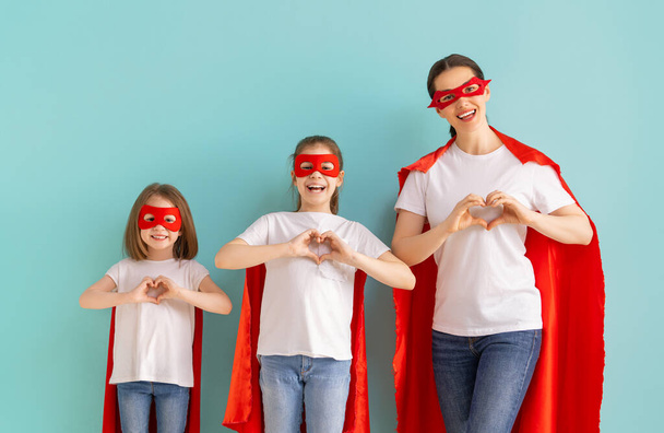 Mother and her children playing together. Girls and mom in Superhero costumes having fun and smiling. Family holiday and togetherness. - Foto, immagini