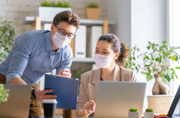 Businessman and businesswoman with medical mask working in office. Covid-19 time. - Photo, Image
