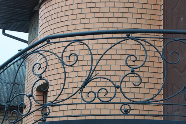 czarne metalowe poręcze z kutym żelazem wzorem na ulicy przy brązowej ceglanej ścianie - Zdjęcie, obraz