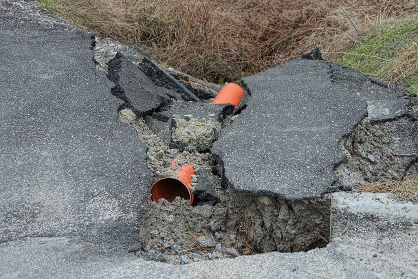 red plastic sewer pipe among pieces of broken asphalt on the road outside - Photo, Image