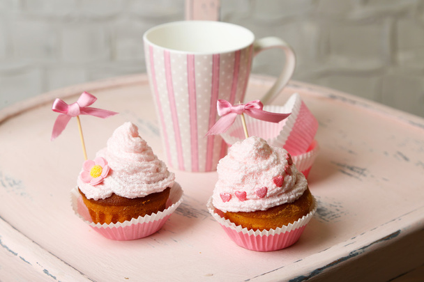 Tasty cup cakes with cream on wooden chair - Foto, afbeelding