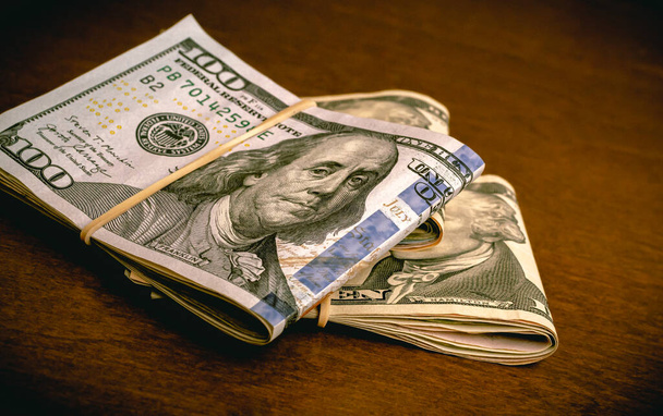 Folded US dollar bills on a wooden desk. Finance, Business, save money and Economy concepts. - Foto, imagen