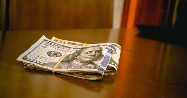 Folded US dollar bills on a wooden desk. Finance, Business, save money and Economy concepts. - Foto, Imagem