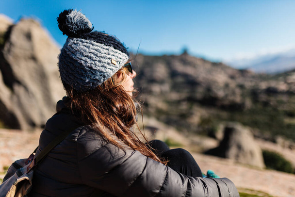 Junge aktive Frau mit Trekkingausrüstung sitzt, entspannt und blickt auf See und Berge Hintergrund - Foto, Bild