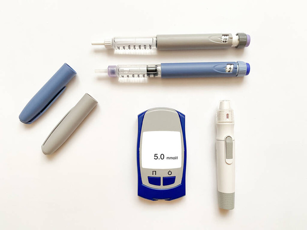 Insulina krótka, długa, glukozomierz, paski testowe i wstrzykiwacz do przekłuwania palców na białym, izolowanym tle. Zestaw dla diabetyków z makietą - Zdjęcie, obraz