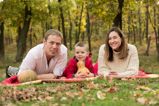 Fall. Close-up of happy family on the background of the autumn forest. Happy mom, dad and son are smiling. - Photo, Image