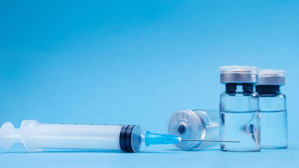 Fiala, flacone, siringa su fondo blu. Concetto di vaccinazione, prevenzione delle malattie. Assistenza sanitaria, sviluppo del vaccino contro il coronavirus - Foto, immagini