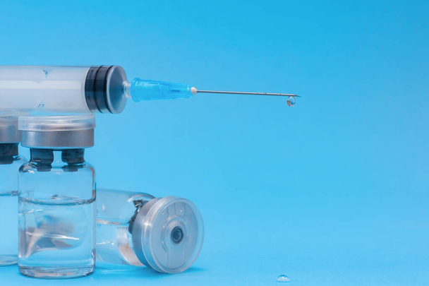 Ампула, флакон, шприц на синем фоне. Концепция вакцинации, профилактика заболеваний. Здравоохранение, разработка коронавирусной вакцины. Селективный фокус - Фото, изображение