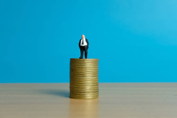 Концепція мініатюрного бізнесу - бізнесмен стоїть над золотими монетами
 - Фото, зображення