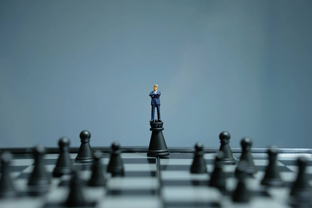 Концептуальна фотографія бізнес-стратегії - мініатюрний бізнесмен, що стоїть над пішаком замку посеред шахівниці
 - Фото, зображення