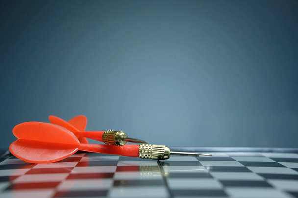 Κόκκινο βέλος βελάκι που βρίσκεται στη σκακιέρα με σκούρο γκρι φόντο. Φωτογραφία εικόνας - Φωτογραφία, εικόνα