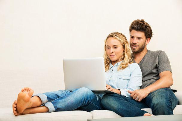Giovane coppia a casa utilizzando il computer portatile
 - Foto, immagini