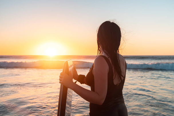 Kobieta z nadwoziem wchodzącym do oceanu o zachodzie słońca, Moana Beach, Australia Południowa - Zdjęcie, obraz