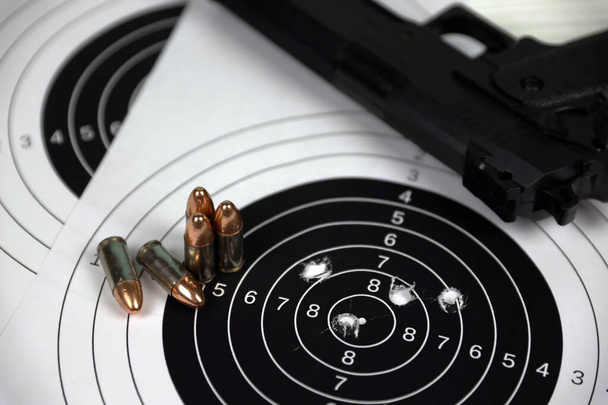 Pistola e molti proiettili sparano bersagli sul tavolo bianco nel poligono poligono di tiro. Formazione per mirare e precisione di tiro - Foto, immagini
