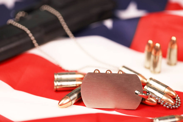 Many yellow 9mm bullets and gun with dogtags on United States flag. - Photo, Image