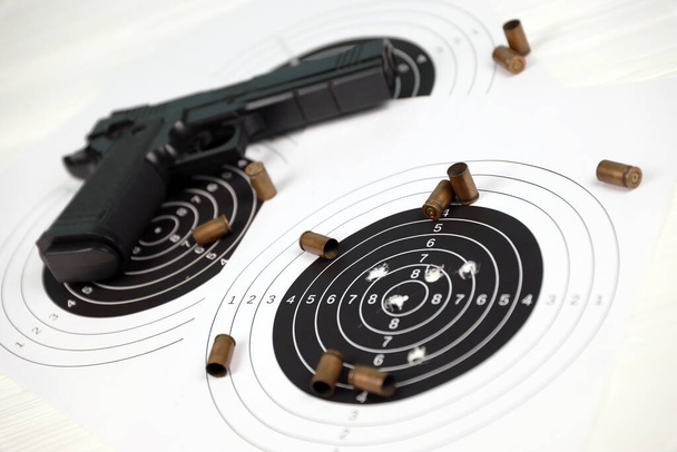 Pistola y muchas balas disparando objetivos en la mesa blanca en el polígono de tiro. Entrenamiento para apuntar y precisión de tiro - Foto, Imagen