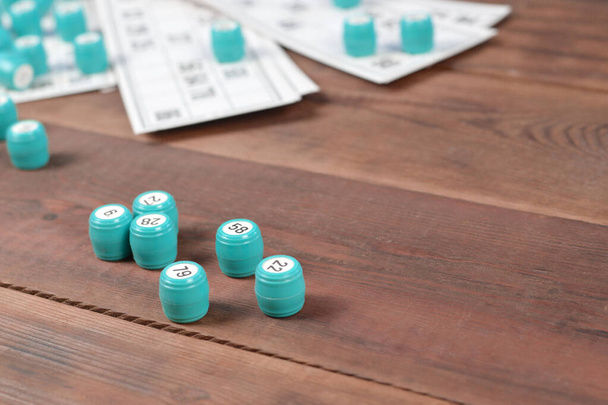 Muchos barriles con números y tarjetas para el juego de mesa de bingo de lotería o ruso en la superficie de madera. Lotería rusa tiene reglas similares a las del bingo clásico mundial - Foto, imagen