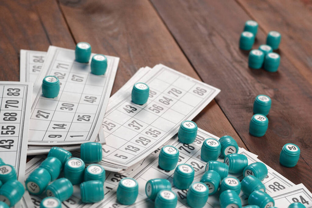 Wiele beczek z liczbami i kartami do gry w lotto lub rosyjski stół bingo na drewnianej powierzchni. Rosyjski lotto ma podobne zasady do klasycznej gry bingo na całym świecie - Zdjęcie, obraz