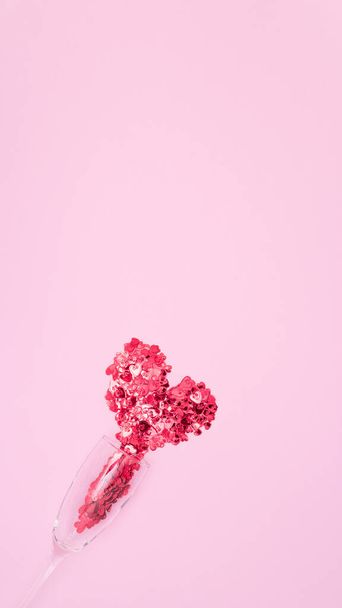 Los corazones rojos fluyen de una copa de champán. Fondo rosa, vista superior. - Foto, Imagen